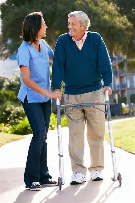 Caregiver walking alongside an older man using a walker