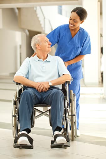 Caregiver standing beside an older man in a wheelchair