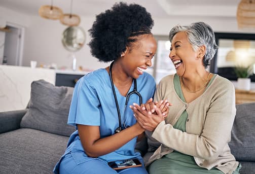 Caregiver and older woman smiling together outdoors